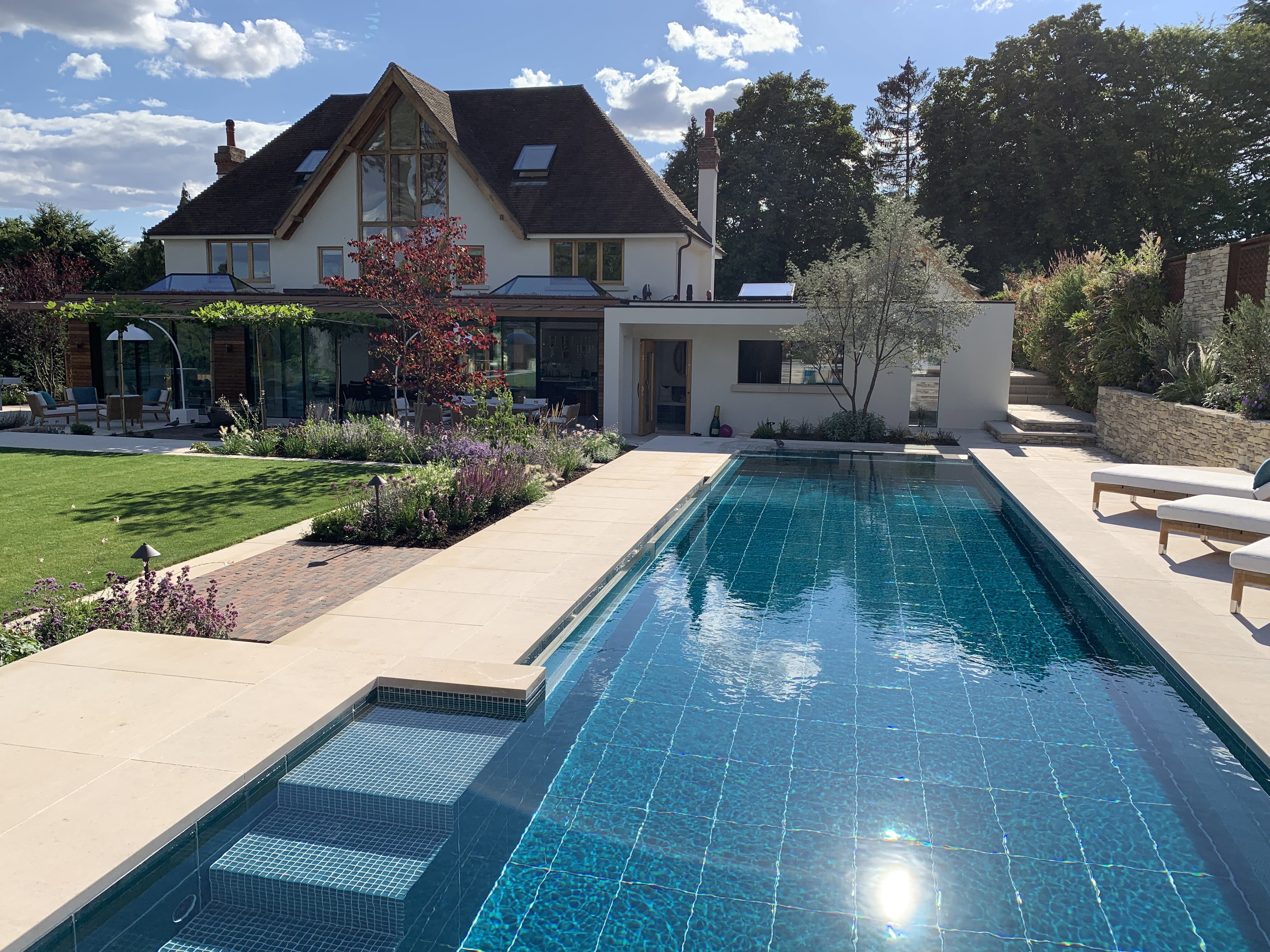 A vibrant lime stone swimming pool with beige stone and blue pool tiles